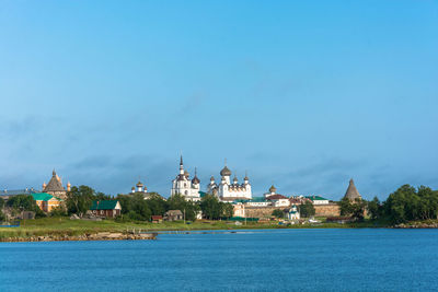 View of buildings at waterfront against blue sky