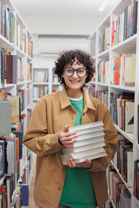 Portrait of smiling young woman using mobile phone in library