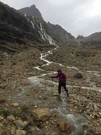 Rear view of woman standing on mountain against sky