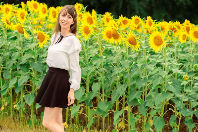 Low section of woman standing on sunflower field