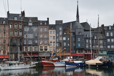 Boats moored at harbor against buildings in city