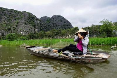 Man rowing boat in lake against sky