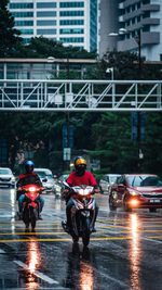 People riding motorcycle on wet street during rainy season