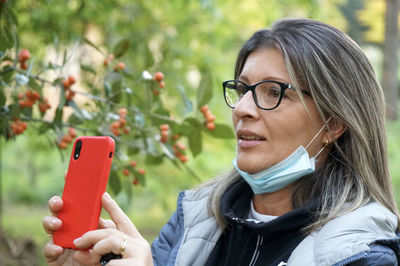 Portrait of woman holding eyeglasses on plant