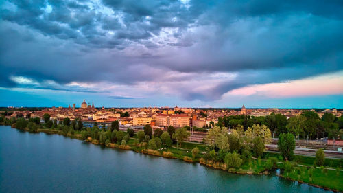 Buildings by river against sky in city