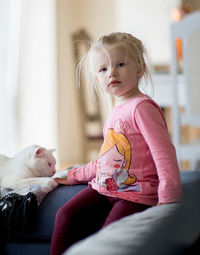 Cute girl sitting with cat on couch at home