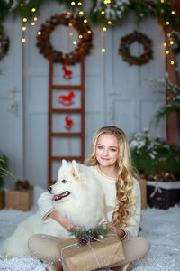 Portrait of young woman with dog on snow