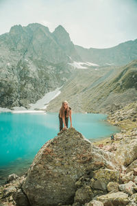 People standing on rock by mountains against sky