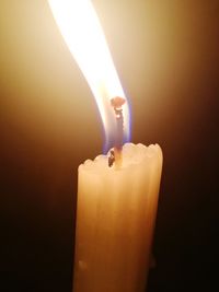 Close-up of illuminated candle in darkroom