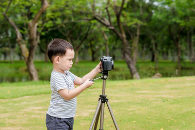 Cute boy photographing while standing at park