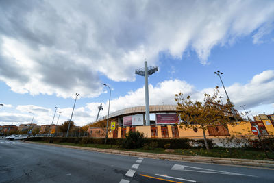 Road by buildings against sky