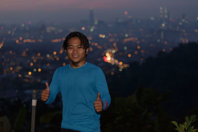 Man standing against illuminated city at night