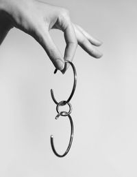 Close-up of hand holding metal against white background