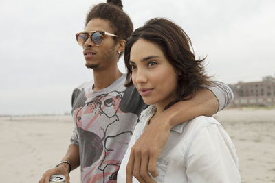 Portrait of young couple on beach against sky