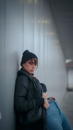 Side view of woman sitting against wall