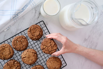 Top view of how a hand holds a delicious homemade cookie on the background of a grid for drying and