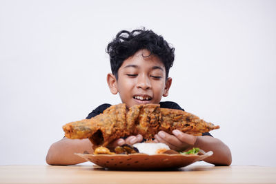 Portrait of cute girl eating food against white background