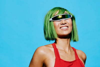 Portrait of young woman wearing sunglasses against blue background