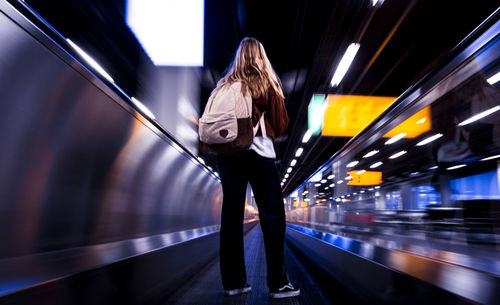 Woman standing on railroad station platform at night
