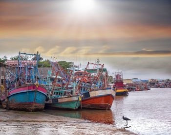 Boats moored at harbor against sky during sunset