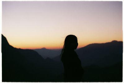 Silhouette woman standing against orange sky