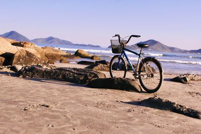 Bicycle on beach against clear sky