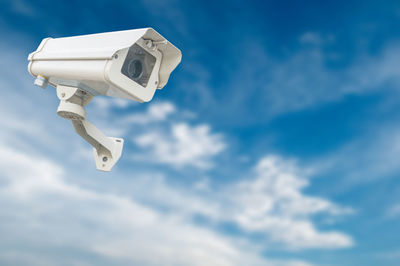 Digital composite image of security camera against blue sky