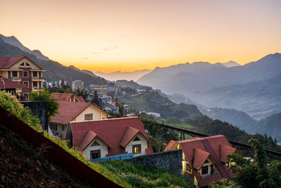 Houses by townscape against sky during sunset