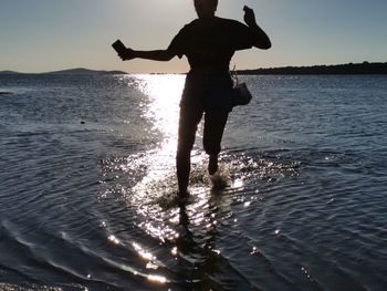 Silhouette man standing on beach against sky during sunset