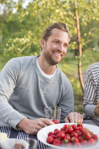 Smiling man having lunch with friend at picnic table