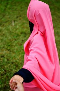 Muslim woman holding hand on field