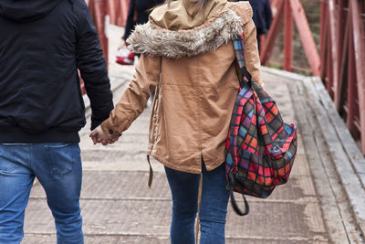 Rear view of friends walking on street in city