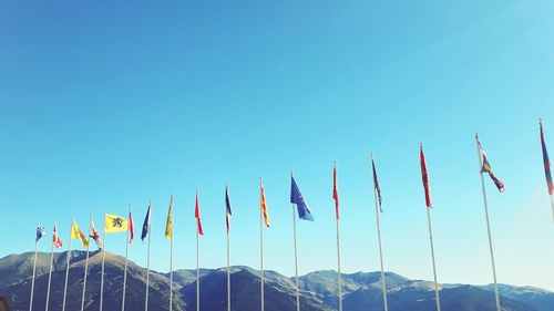 Low angle view of flags against clear blue sky