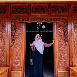 Portrait of young woman standing against door