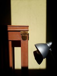 Close-up of electric lamp on table against wall