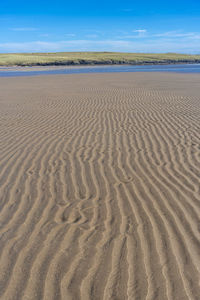 Sand dune on beach against sky