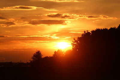 Silhouette trees against dramatic sky during sunset
