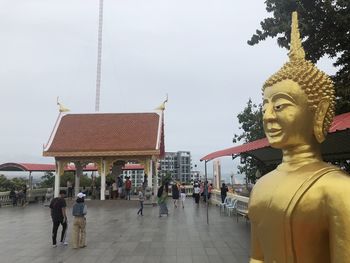 Statue outside temple against building and sky