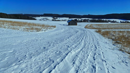 Snow covered field against blue sky