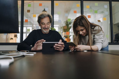 Casual senior buisinessman and girl using tablet and smartphone in office