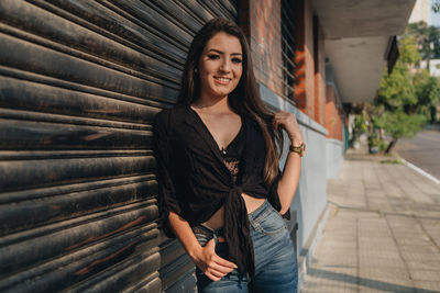 Portrait of woman standing by closed shutter