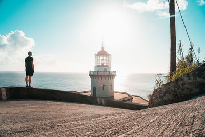 Rear view of man standing by sea against sky