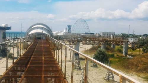 Footbridge over river in city against sky