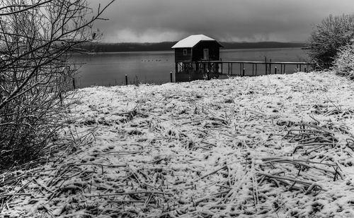 Snow covered field by building against sky