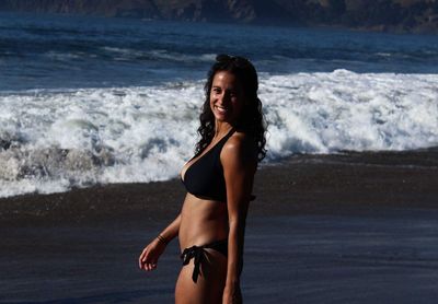 Portrait of smiling young woman standing at beach