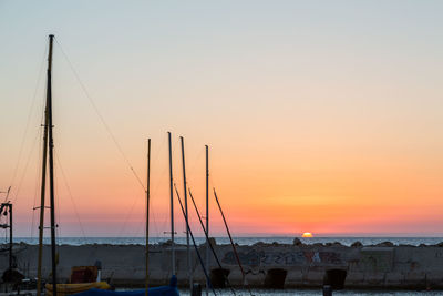 Sailboats moored at harbor during sunset