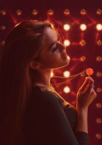 Close-up of young woman holding camera at night