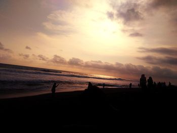 Silhouette people on beach against sky during sunset