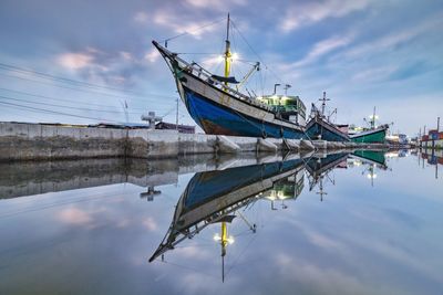 Ships moored at harbor by sea against sky