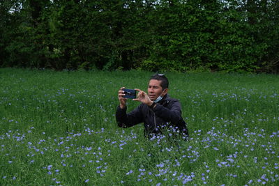 Man photographing on grassy field